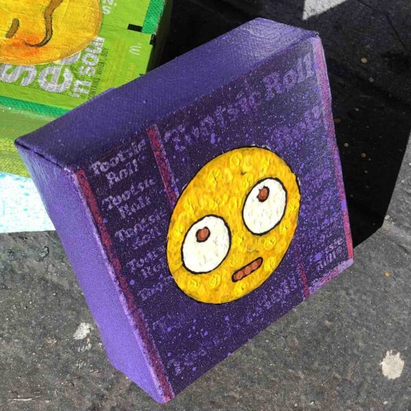 Angled view of Rolling Eye emoji on purple Tootsie Roll wrappers.